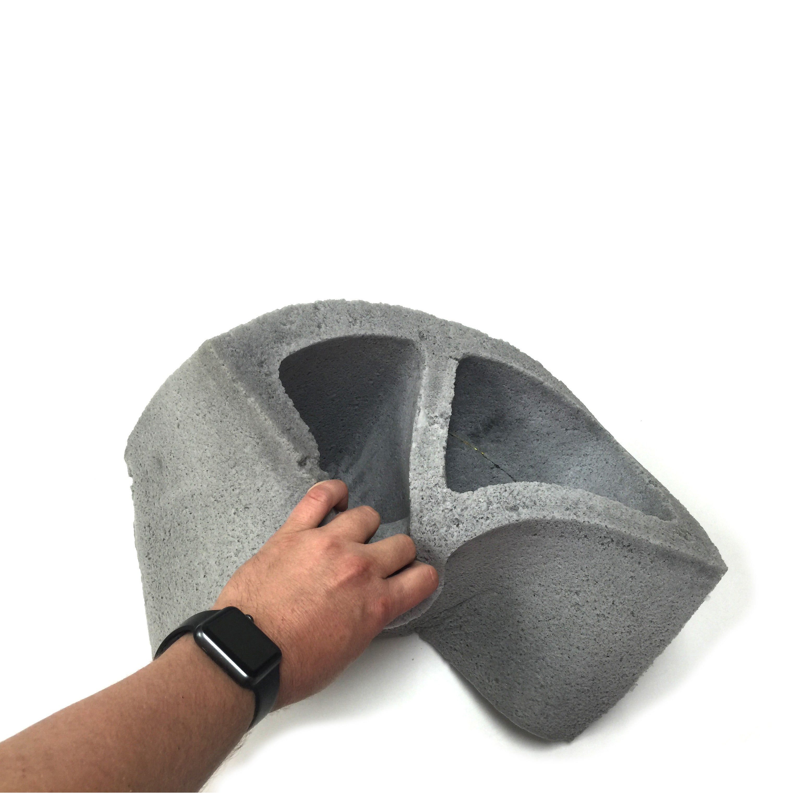Flexible view of a realistic flexible foam prop cinder block with a gray stone color and texture, designed for safe use in stunts, theater, or film