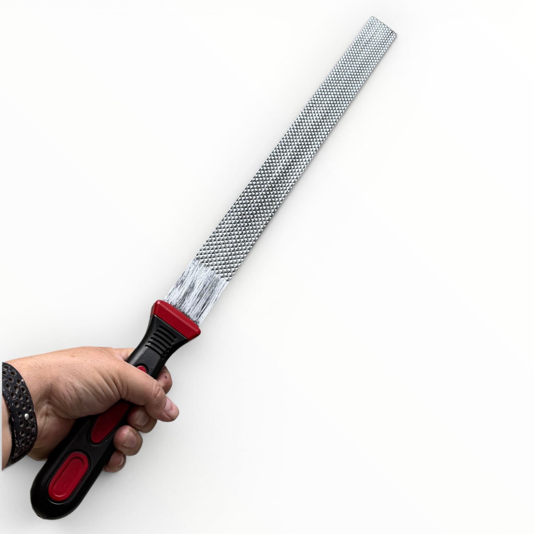 Hand holding a metal file with a red handle on a white background