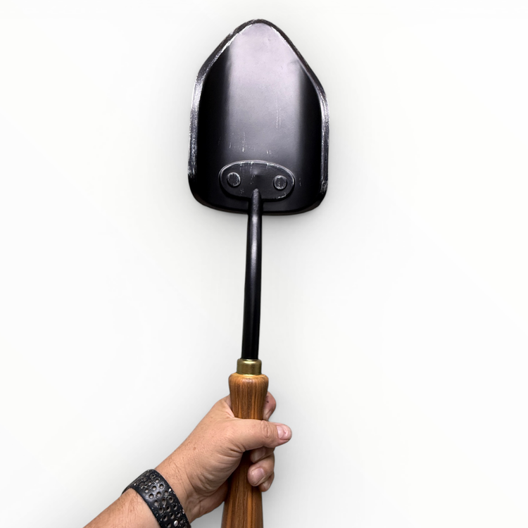 Hand holding a gardening trowel against a white background