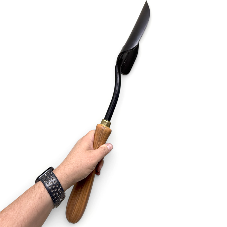 Hand holding a gardening tool with a wooden handle and black blade on a white background