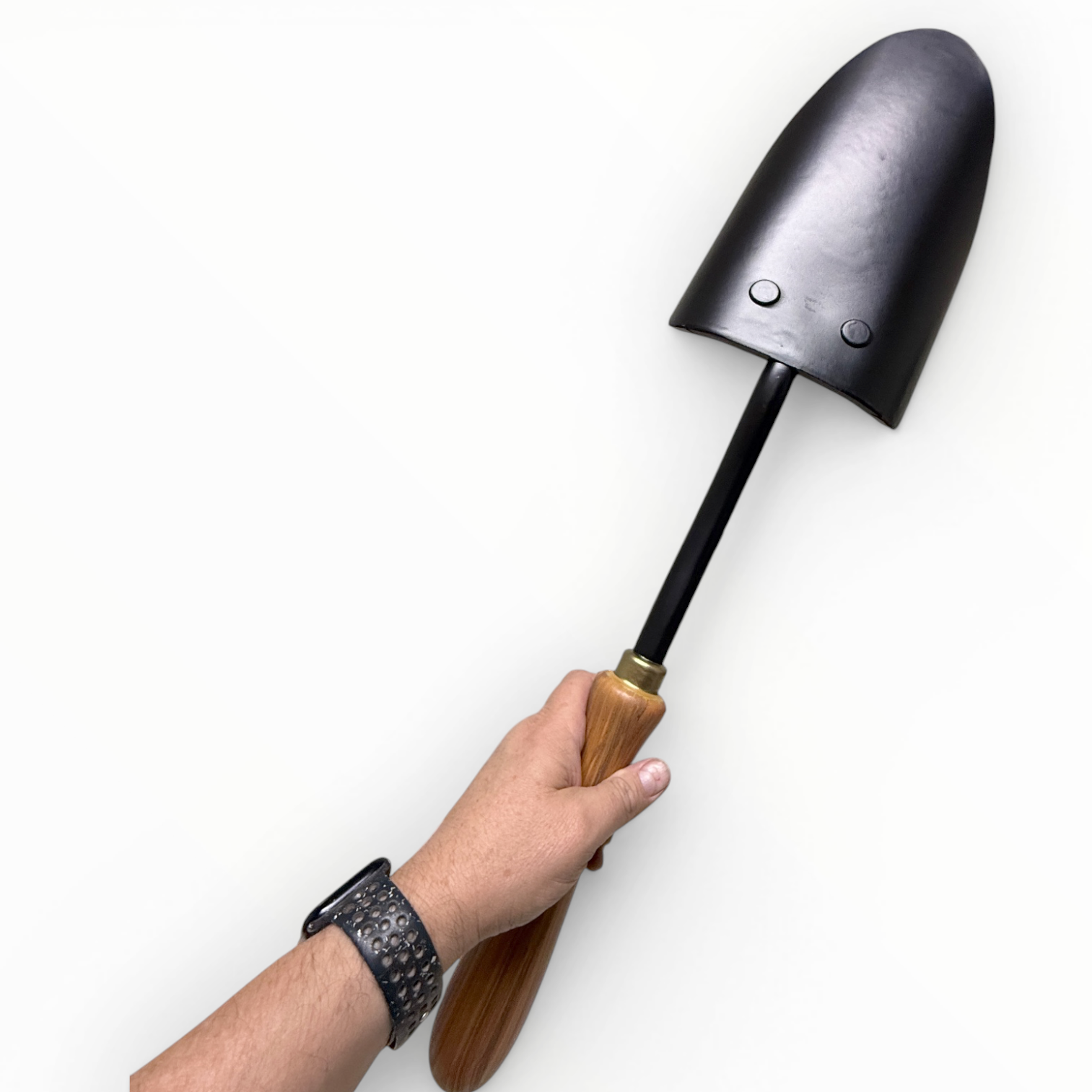 Hand holding a black gardening shovel with a wooden handle on a white background