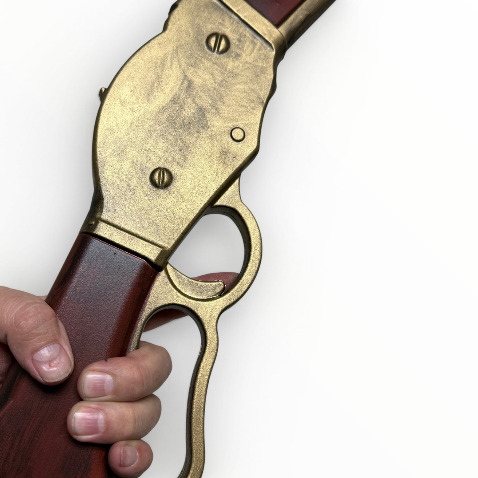 Close-up of a hand holding a revolver with brass and wooden grip on a white background