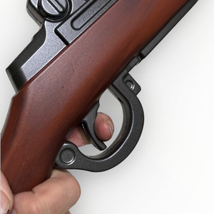 Close-up of a hand holding a rifle with a wooden stock on a white background