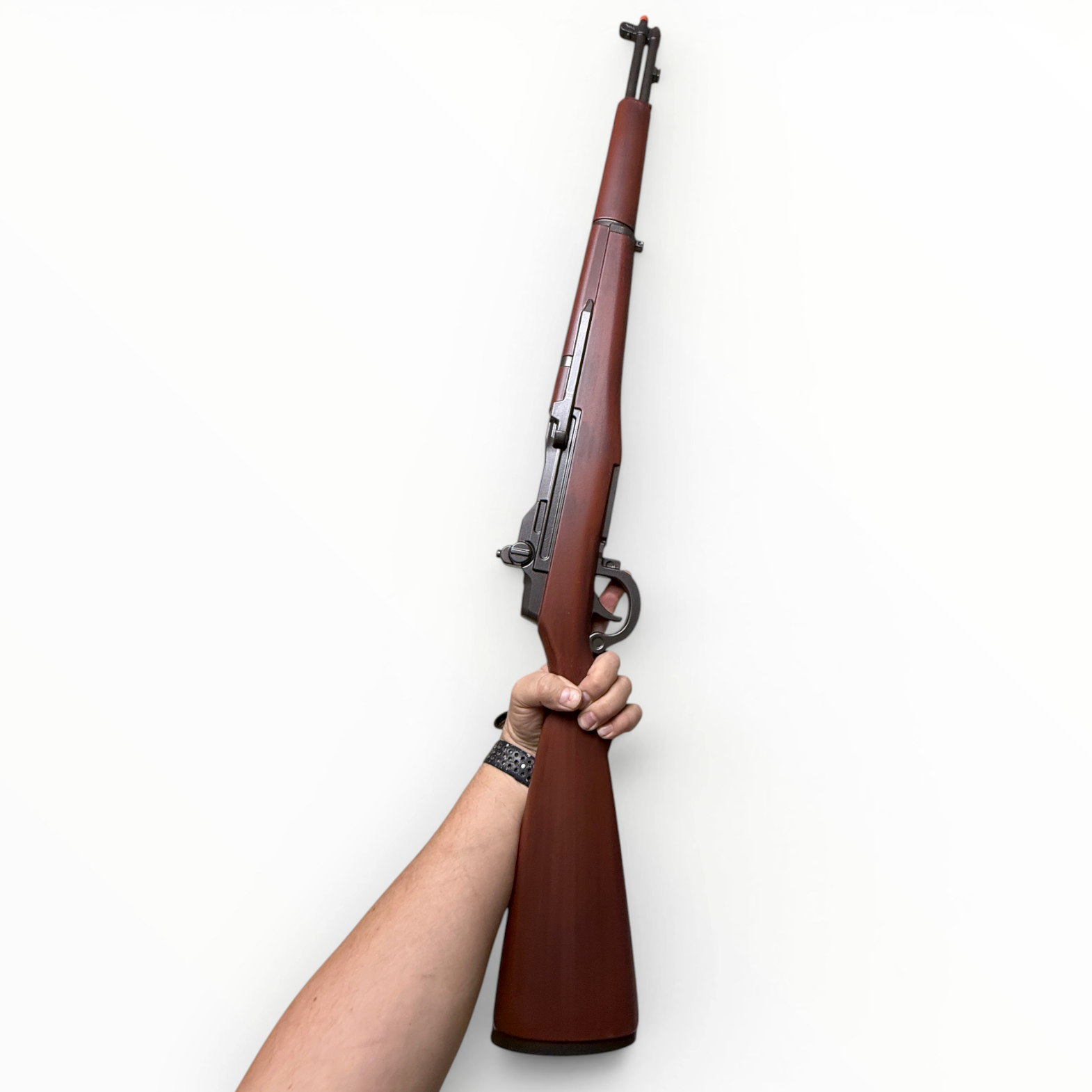 Wooden rifle held by a person's arm against a white background