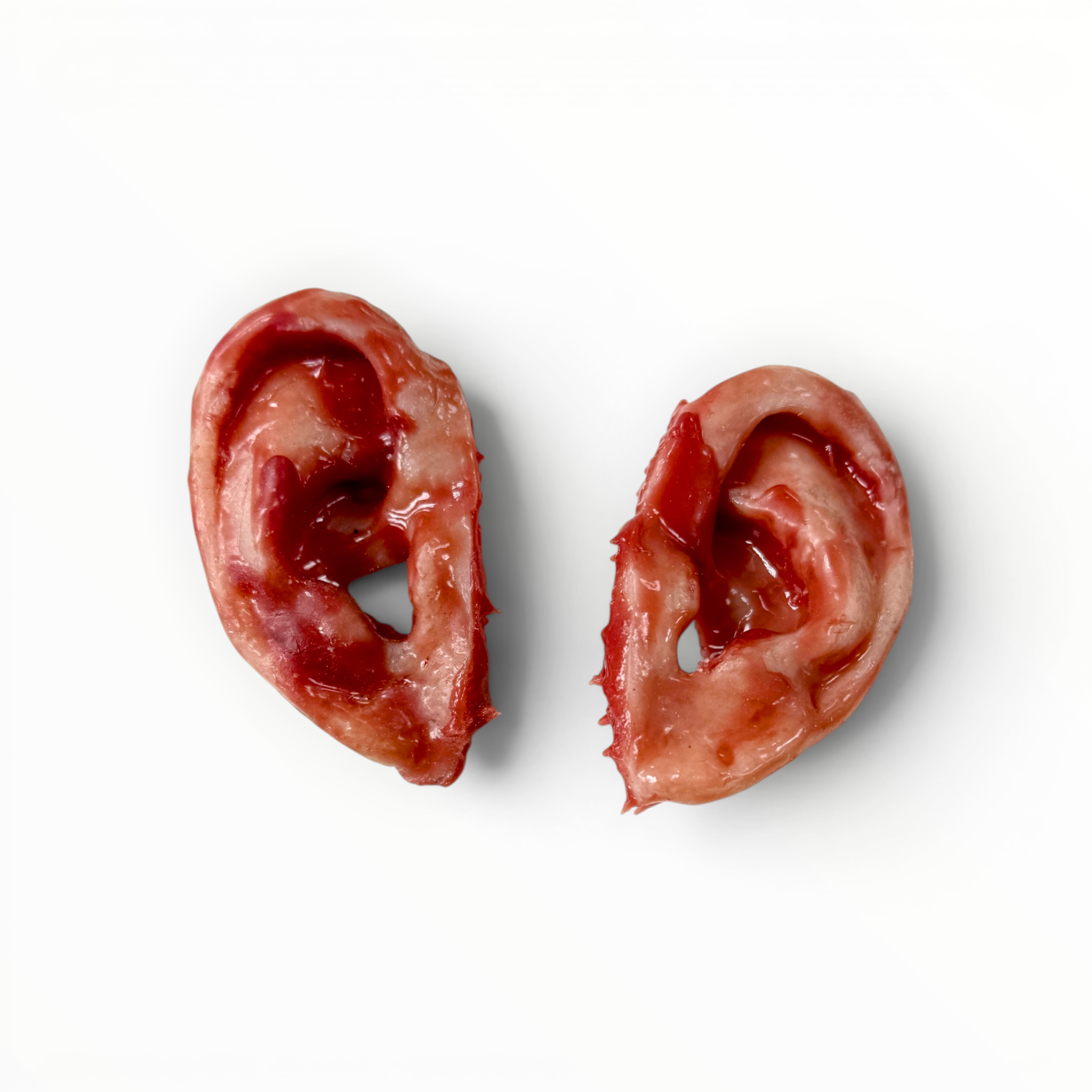 Two bloody silicone ears on a white background