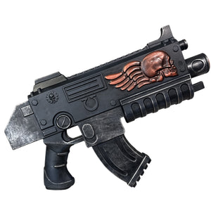 Foam Space Marine Bolter Prop Gun, a sci-fi styled weapon with a dark metal finish, features a copper skull emblem, ergonomic grips, and a chunky, industrial design.