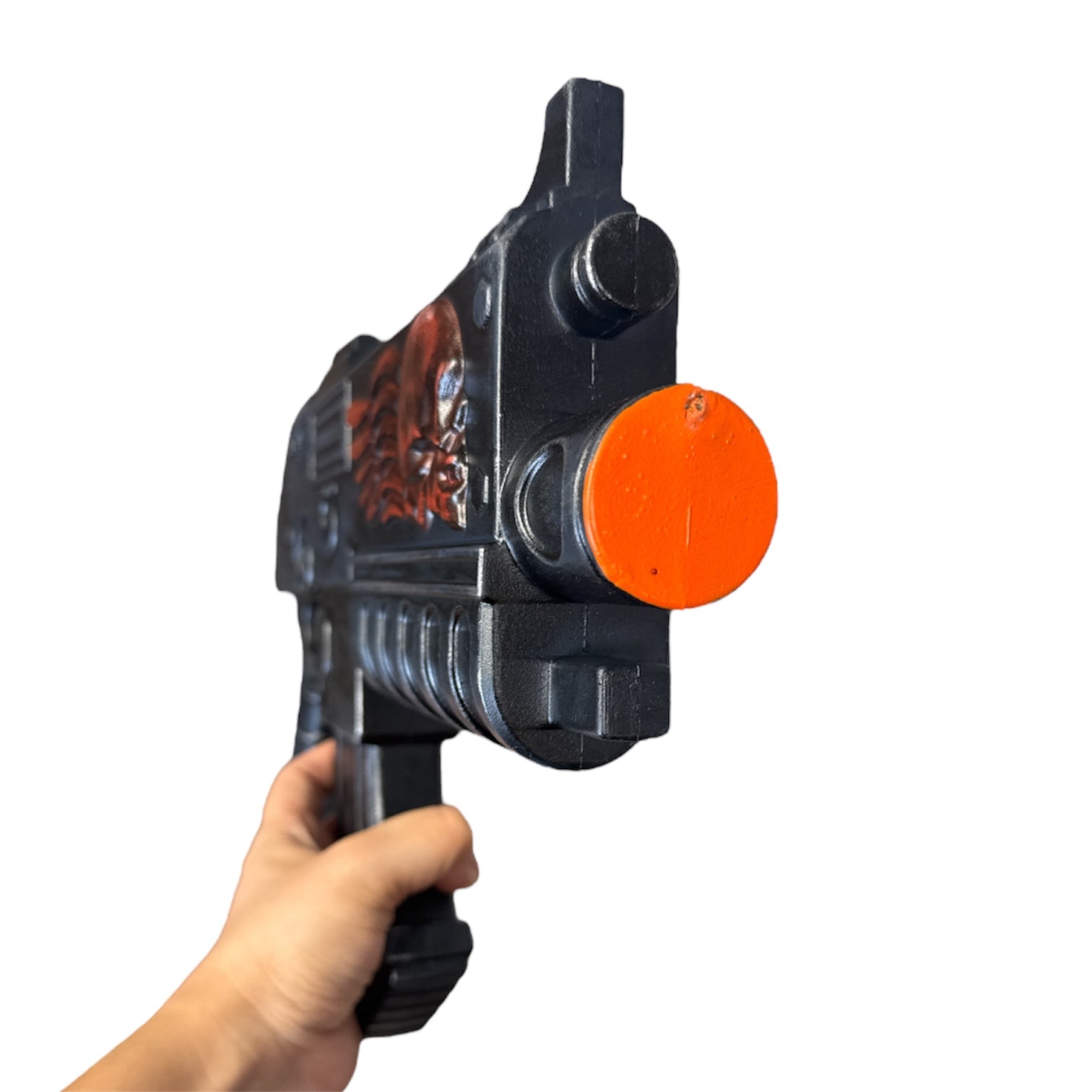Hand holding a Foam Space Marine Bolter Prop Gun with a black body featuring molded details, including a skull relief and an orange safety tip.