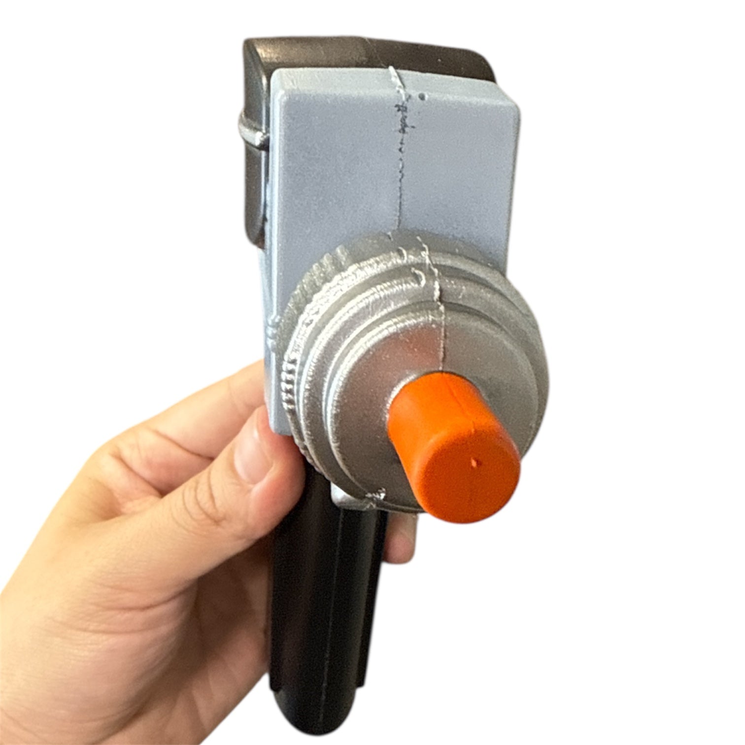Hand holds a Star Trek Phaser prop with a black handle, grey metal body, silver adjustment wheel, and orange tip, designed for realistic special effects use.