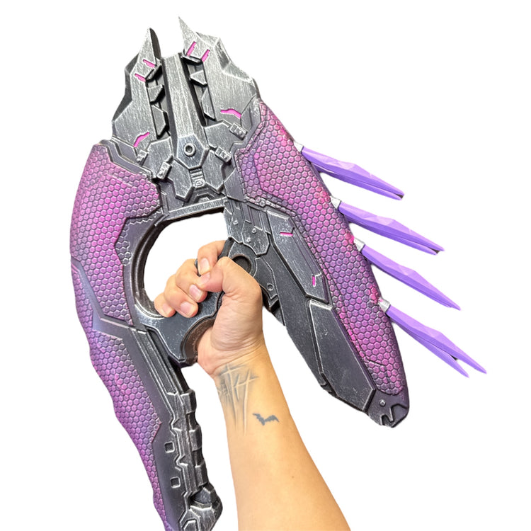 Rubber Halo Needler Prop: A futuristic, sci-fi throwing weapon with a metallic finish, featuring textured purple panels and blade-like fins, ideal for cosplay or special effects.