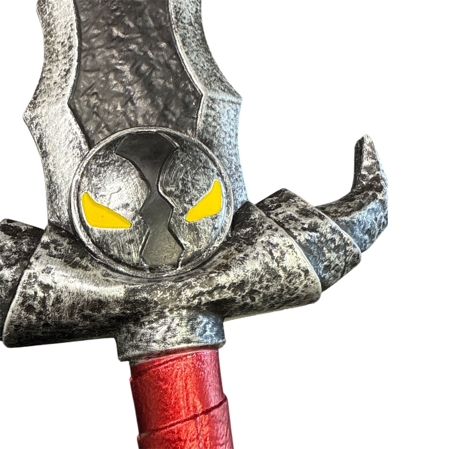 Foam Spawn Sword Prop featuring a weathered metal-like guard with horn-like protrusions, a skull emblem with yellow eyes, and a bright red grip.