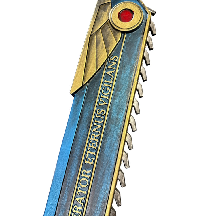 Foam Hell’s Teeth Chainsaw Prop: A detailed, decorative prop sword with gold-blue hues, saw-tooth edge, Latin inscription, and red gem near the hilt for cosplay or display.