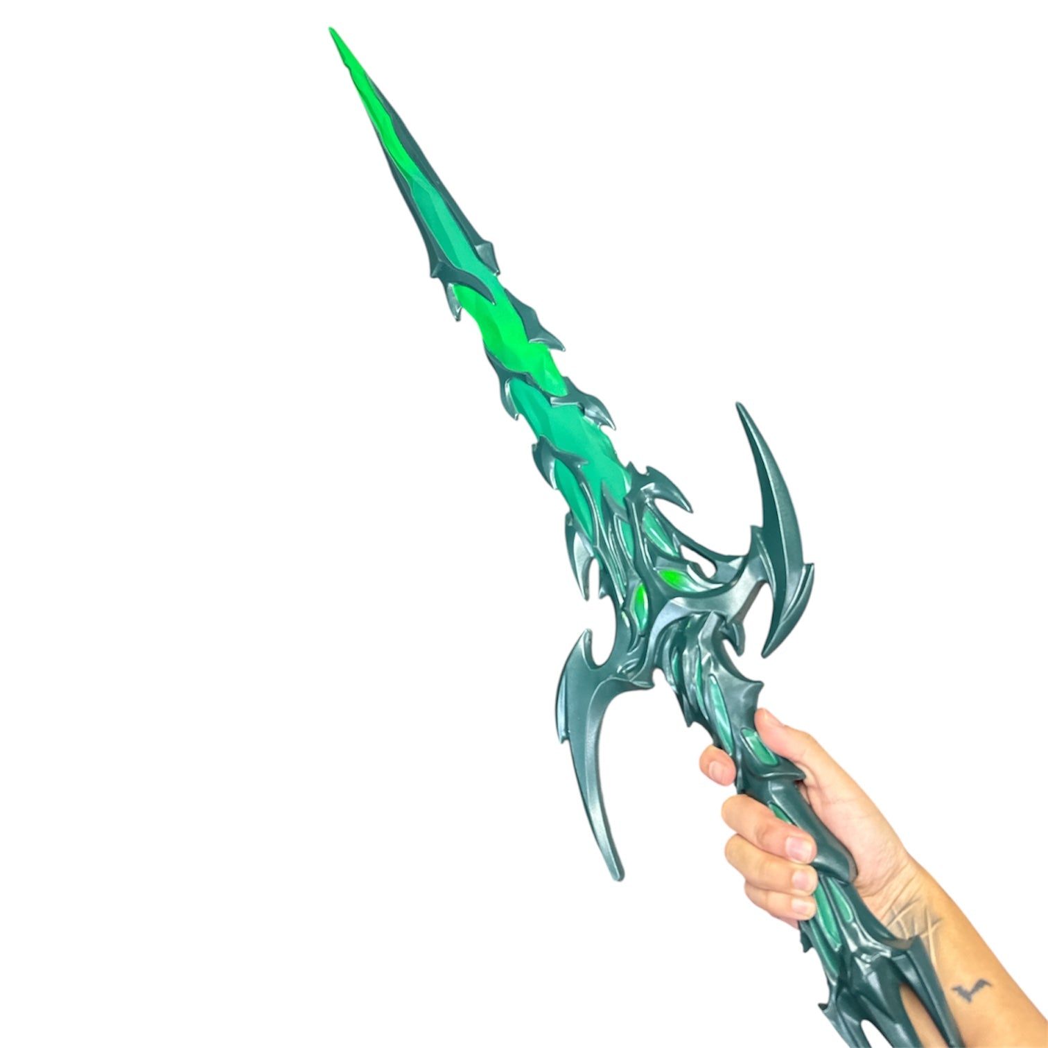 Hand gripping Foam Asgardian Goddess Hela Nightshade Thorn Style Sword Prop, featuring jagged, ornamental design in green and teal hues, measuring approximately 36.25” long.