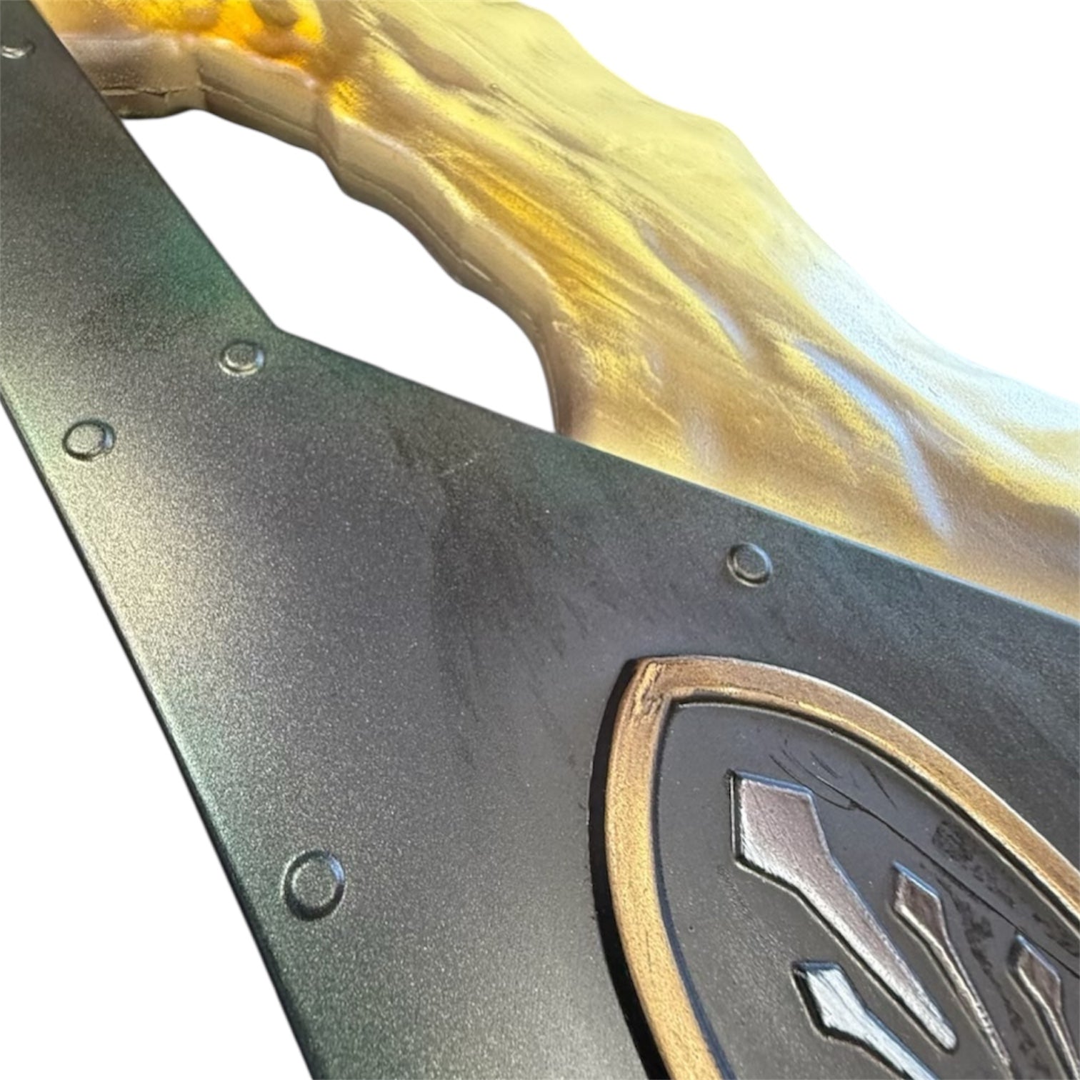 Decorative metal panel with gold-trimmed emblem and wood-grain element, part of Foam Giant Monster Jawblade Sword Prop, measuring 47” x 12” x 4”.