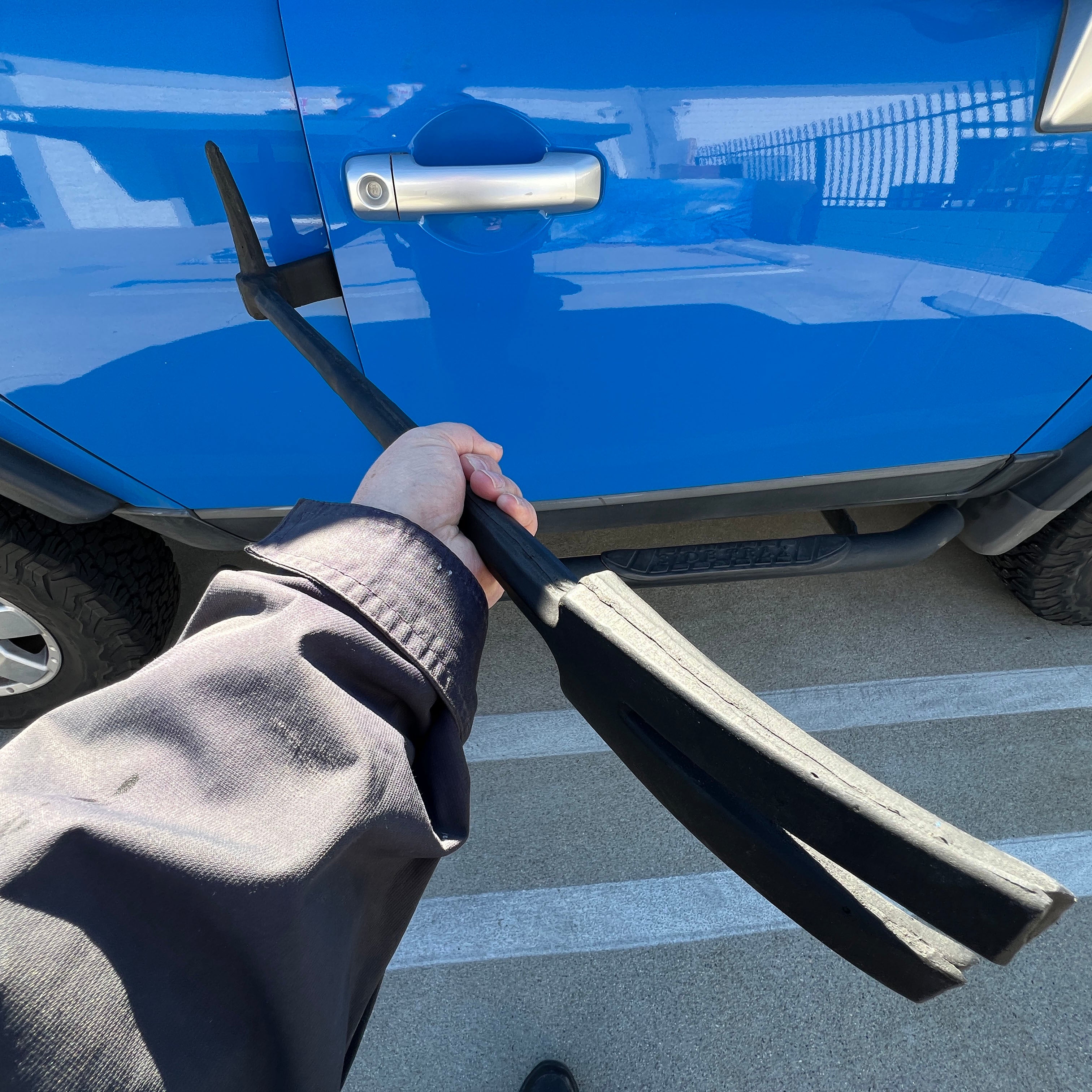 In use view 31 inch foam rubber replica of a firefighter forcible entry rescue bar with a black finish, designed for safe use in stunts, film, or theatrical productions