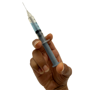 A hand holding a 5ml syringe filled with clear liquid against a solid white background.