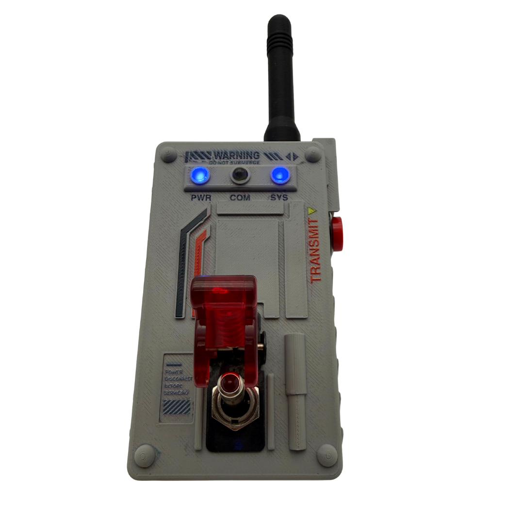 A gray electronic transmitter device with a black antenna, blue indicator lights, a red translucent front light, and red printed text, shown on a plain white background.