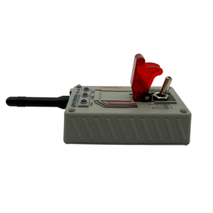 A gray electronic device with a black antenna, a red translucent hinged cover, and a metal contact terminal, photographed on a plain white background.