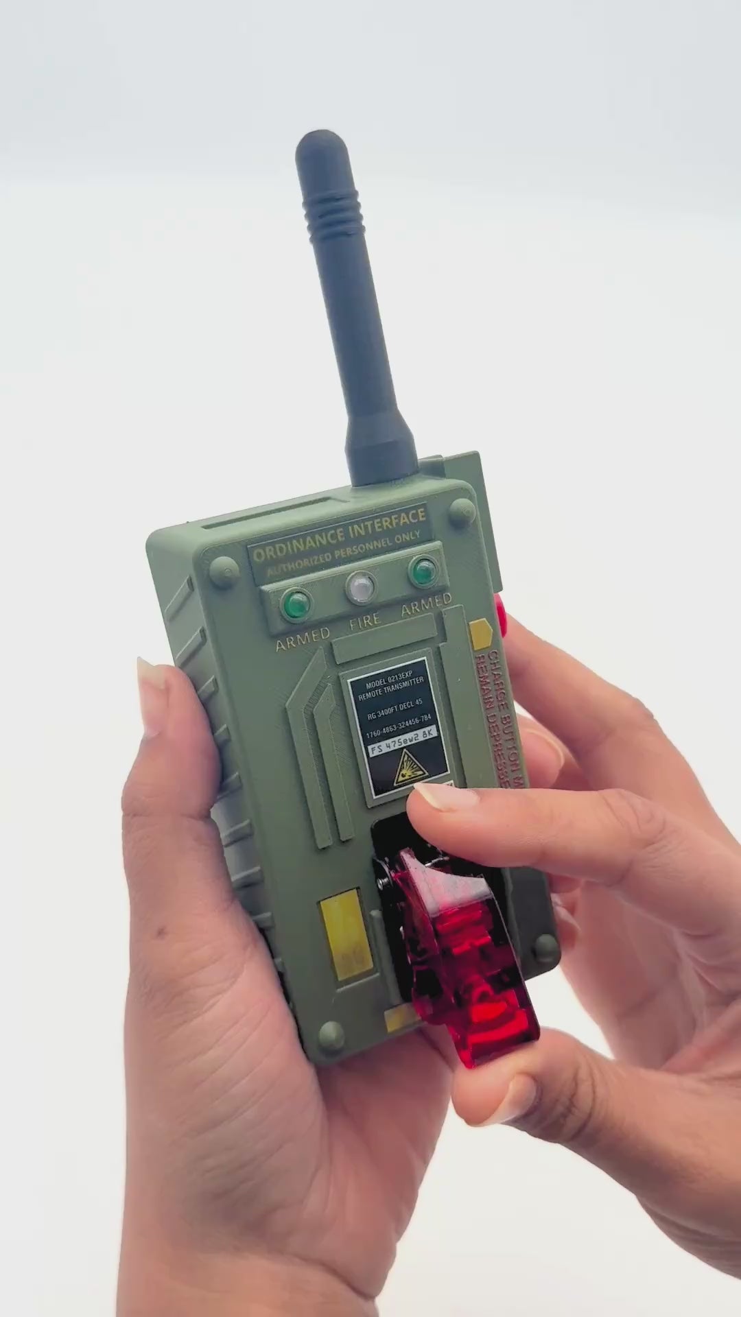 Video of Detonator device being used, hands showing functions of the device. hand flips switch and lights turn on, hand hits button, video cuts to fake earth explosion, video cuts back to hand turning off switch and closing protective switch cover.
